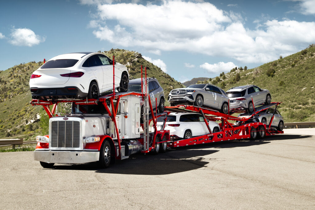 Car hauler loaded with new SUVs parked on a hillside road