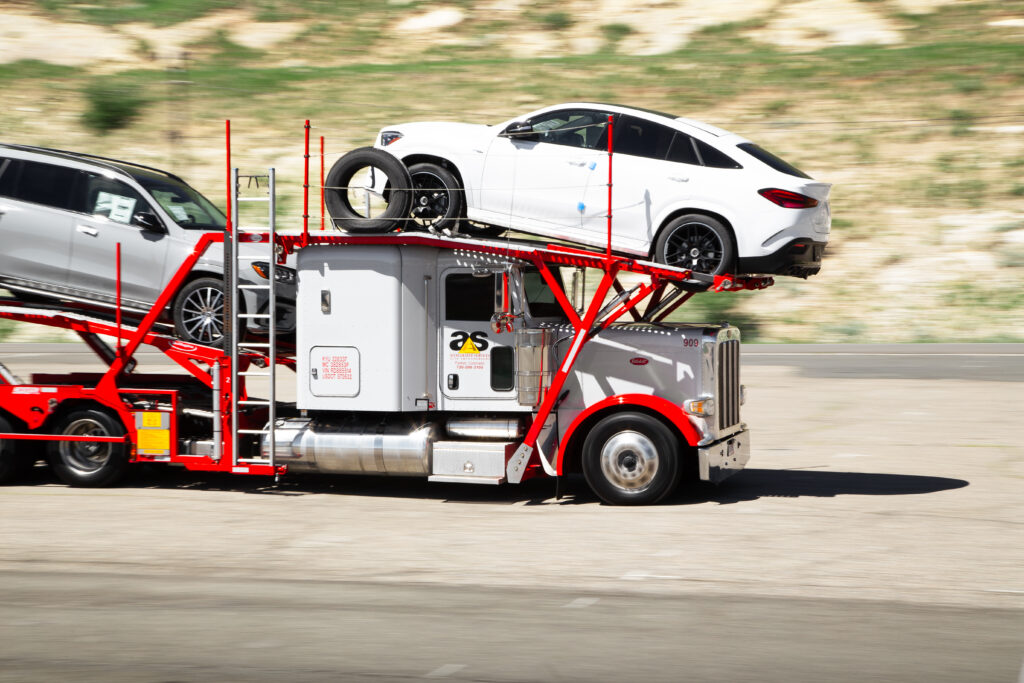 Accelerated car hauler on the move with a white SUV riding over the cab