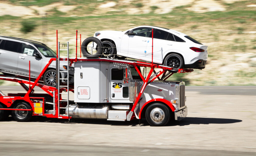 Accelerated car hauler on the highway with a white SUV loaded over the cab